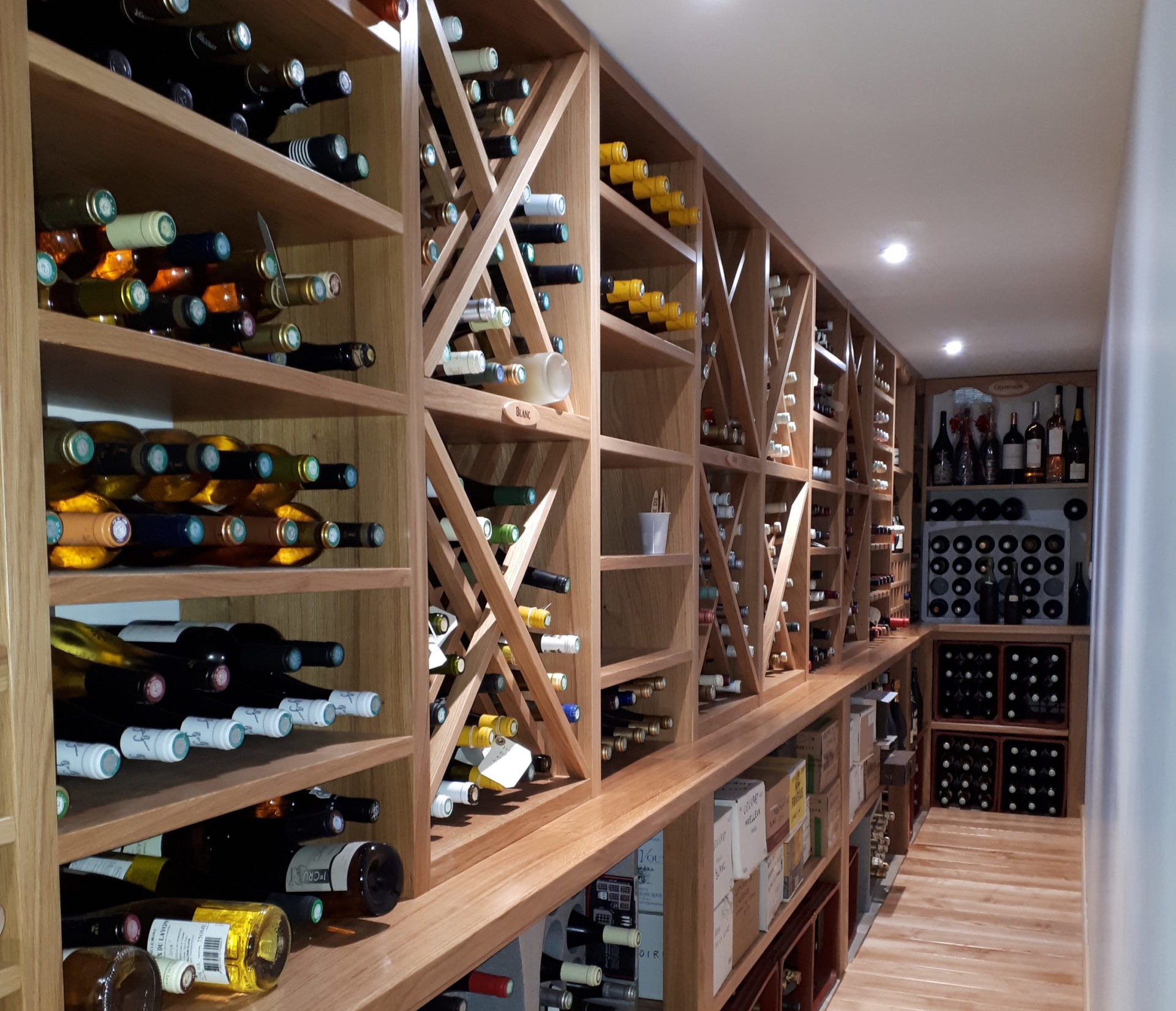 Rangement de cave à vin conçu et réalisé en bois pour suivre la pièce